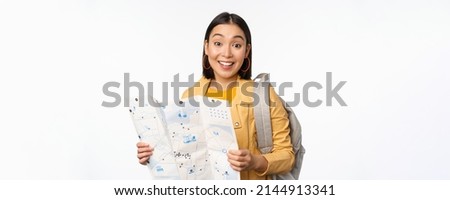Image of young asian girl tourist, traveller with map and backpack posing against white studio background