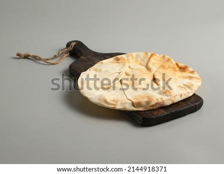 Traditional flatbread lavash on a wooden board, gray background, stock photo