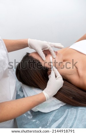 young woman in a beauty center performing a beauty treatment for the skin of the face with the dermaplaning technique Royalty-Free Stock Photo #2144918791