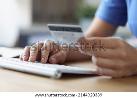 Person holds credit bank card and computer keyboard. Online payments and online money transfer security concept