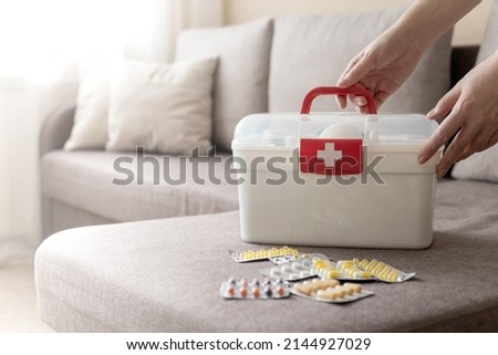 Closeup female hand neatly placing medicament at domestic first aid kit top view. Storage organization in transparent plastic box drug, pill, syringe, bandage. Fast health help safety emergency supply Royalty-Free Stock Photo #2144927029