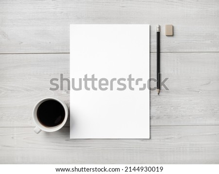 Blank white letterhead, coffee cup, pen and eraser on light wooden background. Royalty-Free Stock Photo #2144930019