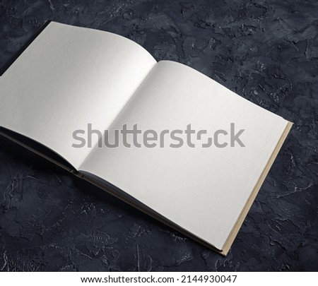 Photo of blank opened notebook on black plaster background. Template for graphic designers portfolios.