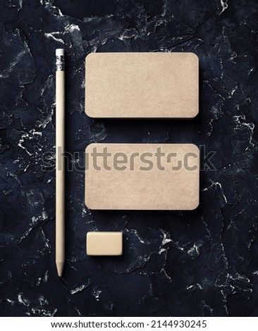 Blank vintage business cards, pencil and eraser on black plaster background. Brand ID mockup. Top view.
