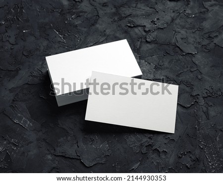 Photo of blank business cards on black plaster background. Mock-up for branding identity. Studio shot.