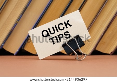 Education and science concept. On the table against the background of books is a business card with the inscription - QUICK TIPS