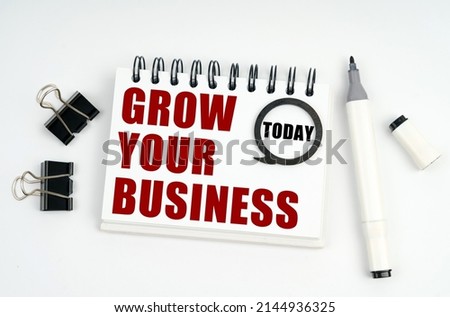Business concept. On a white surface lies a marker, clips and a notebook with the inscriptions Today and GROW YOUR BUSINESS