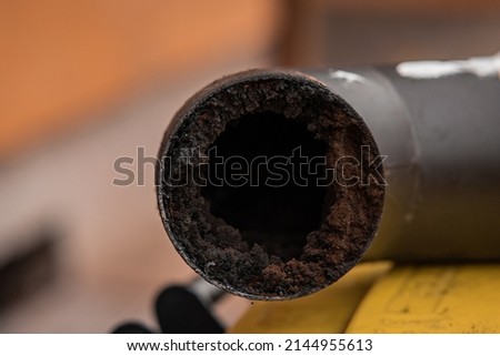 Residue or thick layer of soot after a poor combustion in a fireplace, layered on the inner part of a chimney pipe or smokestack. Dangerous situation for fire, fire hazard. Royalty-Free Stock Photo #2144955613