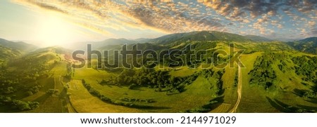 Aerial view of the endless lush pastures of the Carpathian expanses and agricultural land. Cultivated agricultural field. Rural mountain landscape at sunset. Ukraine.