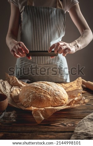 A baker is taking pictures of homemade fresh bread on his phone for a post on social networks. The concept of baking bakery products