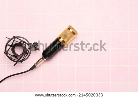 Stand with modern microphone on color background