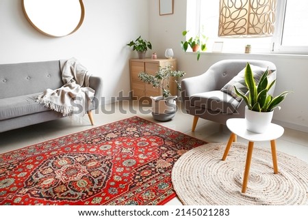 Interior of cozy living room with armchair, houseplants and vintage carpet Royalty-Free Stock Photo #2145021283