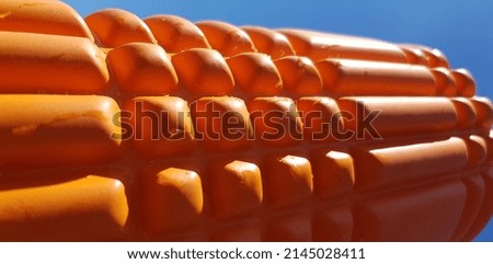 Orange yoga roller in drops in the sun (macro, angle, diagonal, texture).