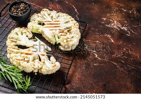 Grilled cauliflower steak with rosemary and spices, Vegan cuisine. Dark background. Top view. Copy space.
