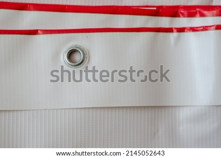 Red and white advertising banner with metal eyelets. Wide-format printing products. Folded banner in close-up