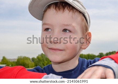 caucasian boy in a baseball cap smiles and dreams looks into the distance green park