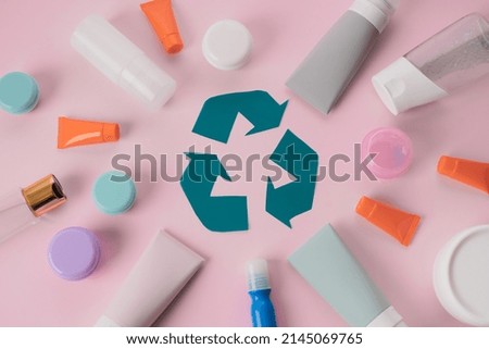 Plastic recycling sign. Used cosmetic tubes and beauty products on pink background. Save the planet. flat lay. top view. High quality photo