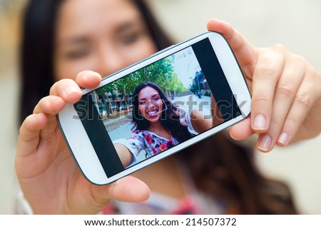 Outdoor portrait of pretty student girl taking a selfie.