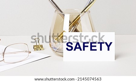 Work desk with gold glasses, pen, white card with the text SAFETY. Business concept. Home Office. Workplace close-up.