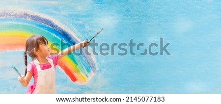 Banner of asian little girl is painting the colorful rainbow and sky on the wall and she look happy and funny, concept of art education and learn through play activity for kid development. Royalty-Free Stock Photo #2145077183