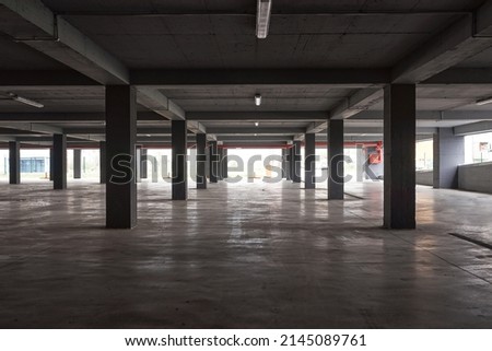 Empty underground parking lot garage interior with concrete columns.
