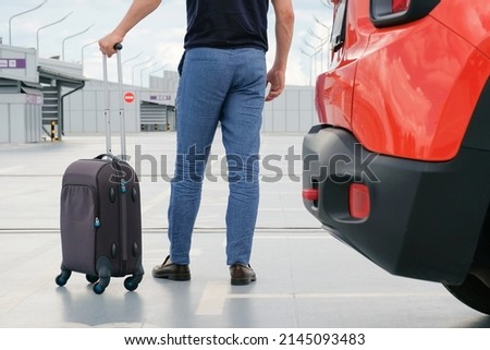 Cropped view of passenger with suitcase in car parking. Tourism, business trip, vacation