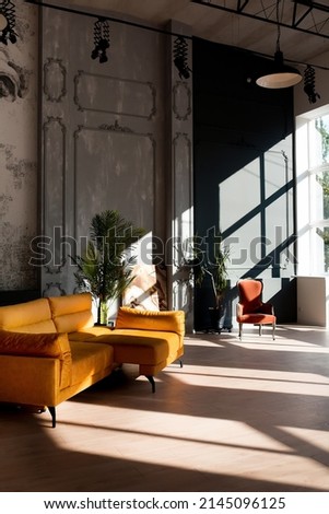 Modern loft living room with high ceiling, black and grey walls, wooden floor, design furniture and tropical plant Royalty-Free Stock Photo #2145096125