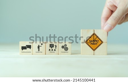 Safety success in the workplace concept.  Hand placed wooden cubes with safety first sign standing with the icon of communication, leadership, training and compliance. Industrial safety banner. 