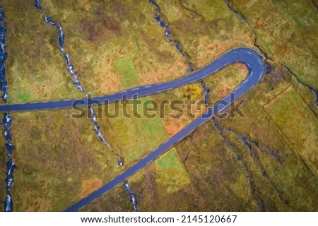 Curvy Road in Kalsoy island, Faroe islands, Denmark. Aerial vertical drone picture in November 2021