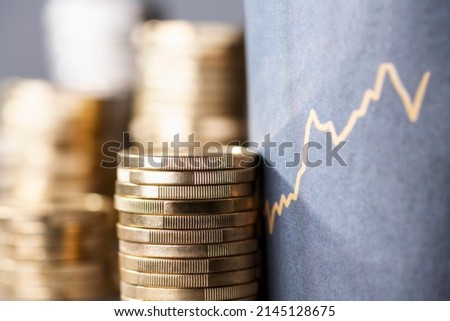 Stack of coins next to a upward curve symbolizing rising costs due to inflation Royalty-Free Stock Photo #2145128675