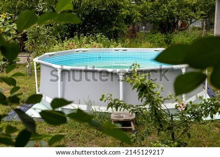 Grey frame swimming pool on the green lawn with trees background