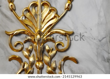 Ancient vintage golden decoration fragment, wooden carving over gray marble wall, close-up photo
