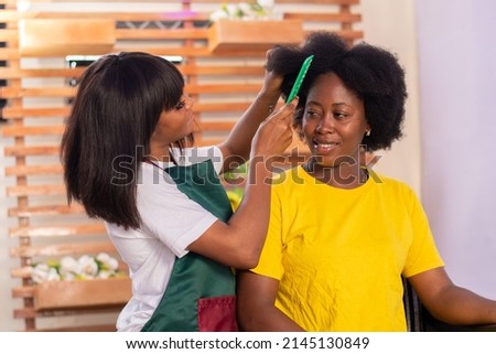 african hairstylist working on a lady's hair