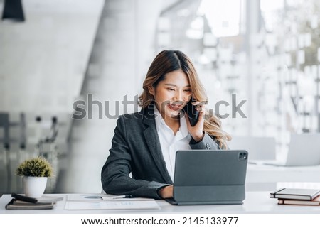 Asian woman talking on the phone, she is a salesperson in a startup company, she is calling customers to sell products and promotions. Concept of selling products through telephone channels. Royalty-Free Stock Photo #2145133977