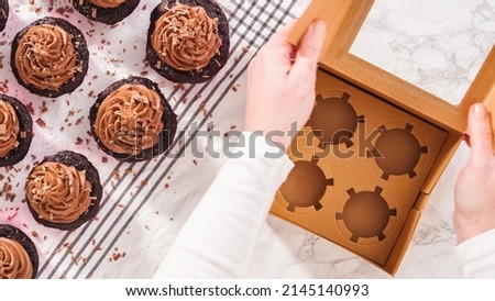 Flat lay. Step by step. Packaging chocolate cupcakes with chocolate ganache frosting into a paper cupcake box.