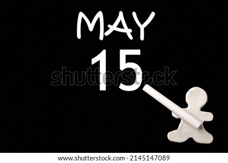 15th day of May. A small white plasticine man writing the date 15 May on a black board. Business concept. Education concept. Spring month, day of the year concept.
