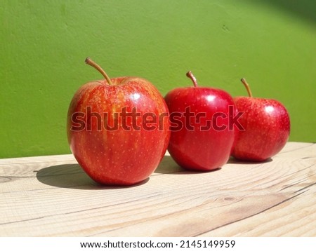 Three red apples placed on a wooden table