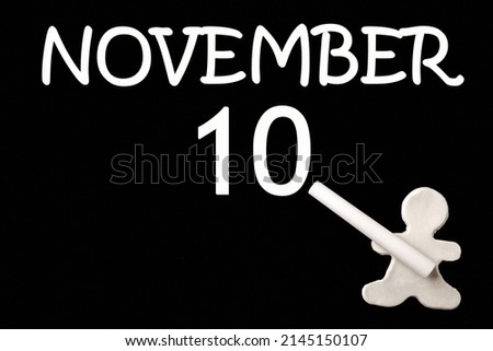 10th day of November. A small white plasticine man writing the date 10 November on a black board. Business concept. Education concept. Autumn month, day of the year concept.