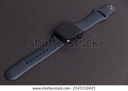 A smartwatch isolated on a black background. Black smartwatch with insulated wrist with open strap. Modern design for high-tech smartwatch and sport technology concept. Close up. Top side view.