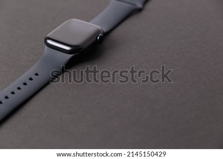 A smartwatch highlighted on a black background. Black smartwatch with insulated wrist and open strap. Modern design of high-tech smart watches and the concept of sports technology. Place to copy