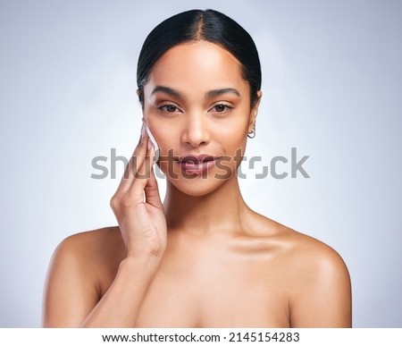 Pat, pat, pat. Shot of an attractive young woman using cotton pads to on her face against a grey background. Royalty-Free Stock Photo #2145154283