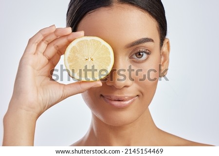 Add a boost of brightness to your beauty routine. Studio shot of an attractive young woman holding a lemon against a grey background.
