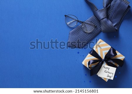 Fathers day background with gift box, necktie, glasses on blue. Happy Fathers Day greeting card design. Royalty-Free Stock Photo #2145156801
