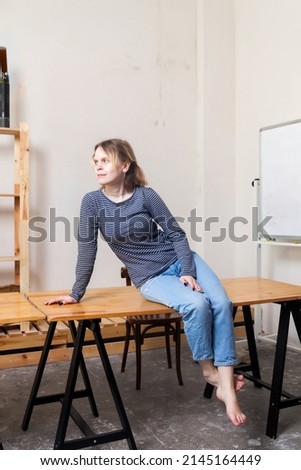Portrait of   teenage girl in   blue striped sweatshirt in   bright interior.

