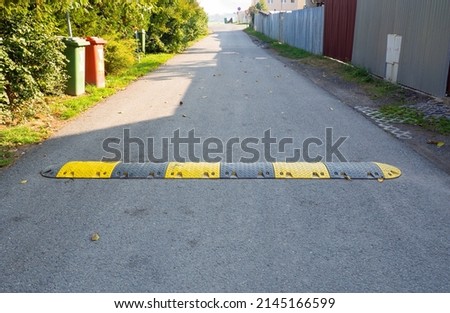 Speed bump on the road, yellow and black striped speed bump in asphalt road to slow down fast moving cars Royalty-Free Stock Photo #2145166599