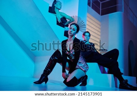 Teenage female leader of vogue dance performance group and two more dancers in posh apparel sitting in front of camera in studio Royalty-Free Stock Photo #2145173901