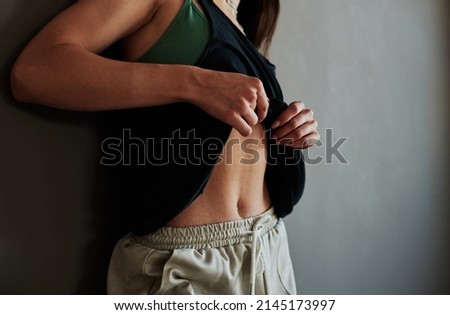 Young contemporary sportswoman or dance performer having rest after training and fanning her sweaty body with tanktop Royalty-Free Stock Photo #2145173997