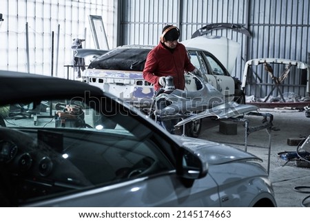Car service worker repairs restores car Royalty-Free Stock Photo #2145174663