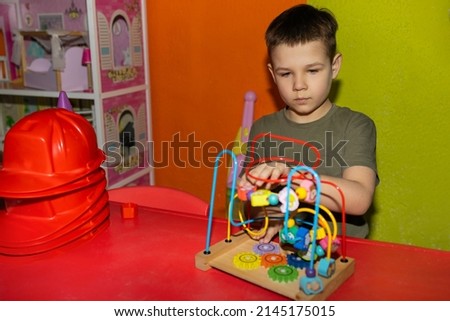 The boy at the table in the playroom plays an educational game. The concept of development of preschool children. The designer develops fine motor skills of hands.