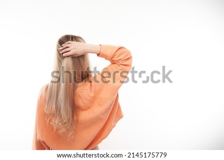 Smart blonde girl in casual holding her head thinks doubts, makes decision isolated on white studio background, back view